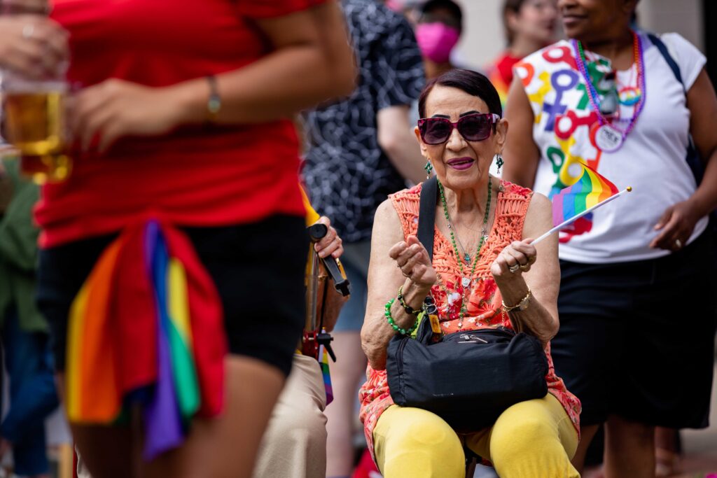 An older woman enjoys Pride 2022, waving a pride flag.